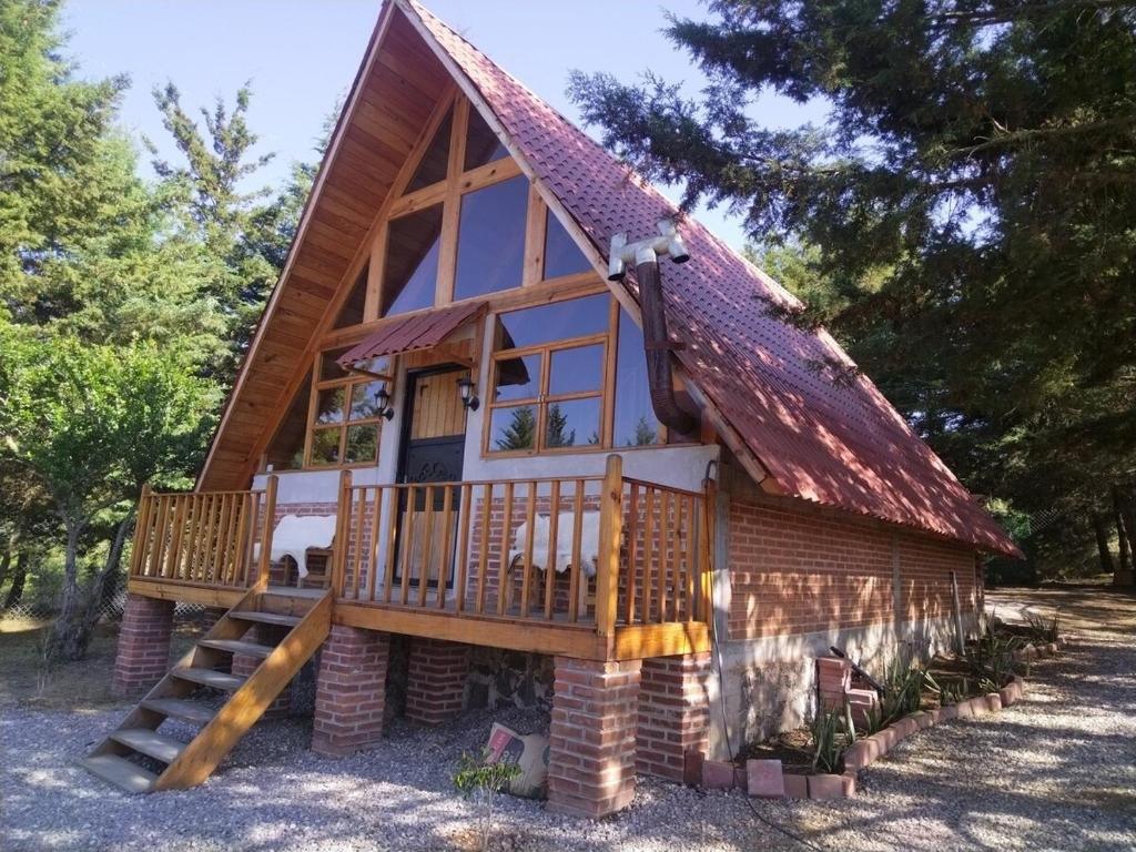 Foto referencial de cabaña de madera y ladrillo con terraza